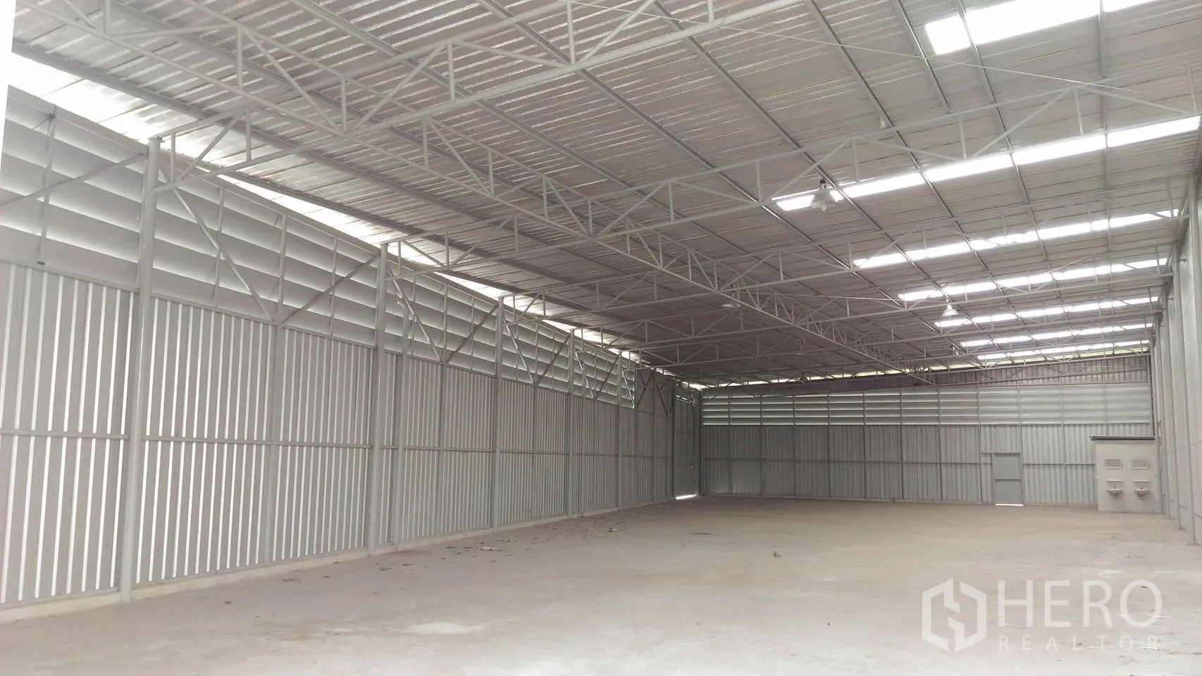 Warehouse for rent in Lam Luk Ka, Pathum Thani - Spacious warehouse interior with steel trusses, louvered ventilation and skylights above a smooth concrete floor.