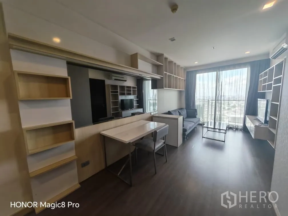 公寓 for rent in Watthana, Bangkok - 客厅设沙发、电视柜与餐桌，落地门通向阳台可观天际线。
