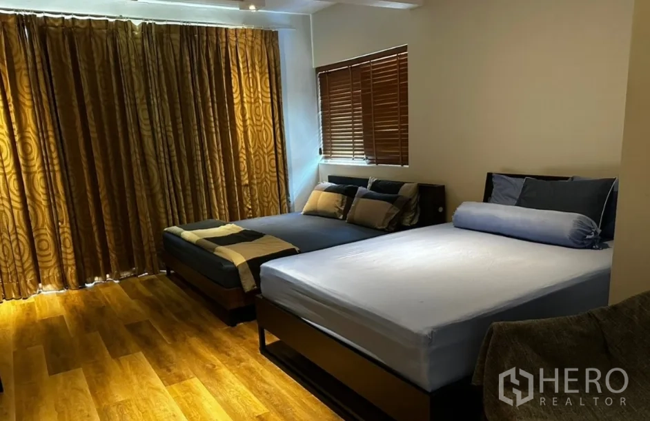 Townhouse for rent in Sathon, Bangkok - Spacious bedroom with two beds, wood flooring, and window blinds.