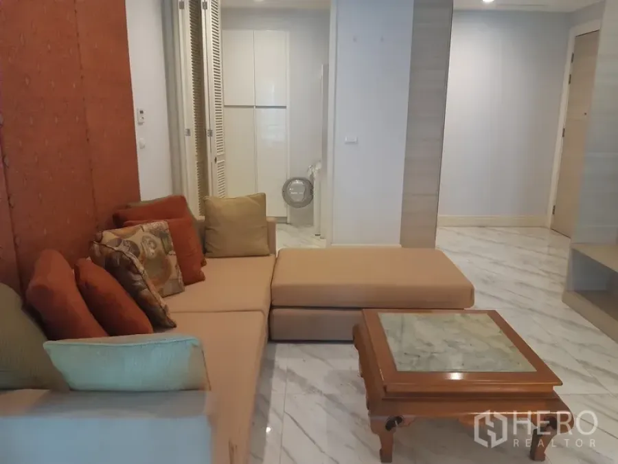 Condominium for rent or sale in Khlong Toei, Bangkok - Cozy lounge with sectional sofa, marble-top coffee table and sleek flooring beside the entry hall.