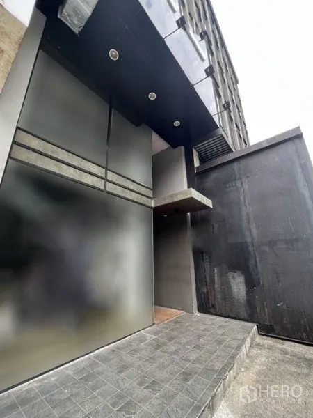 Shophouse for rent - Modern shophouse entrance with dark facade, frosted glass and a tiled ramp.