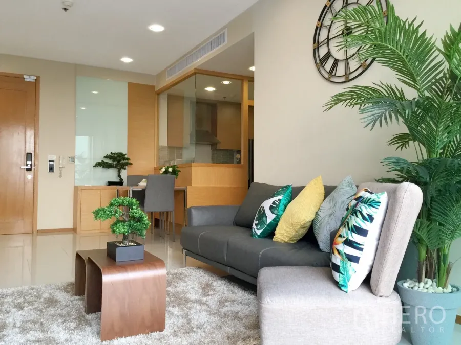 Condominium for rent or sale in Khlong Toei, Bangkok - Living area with sofa set, indoor plants and a dining nook beside the kitchen.