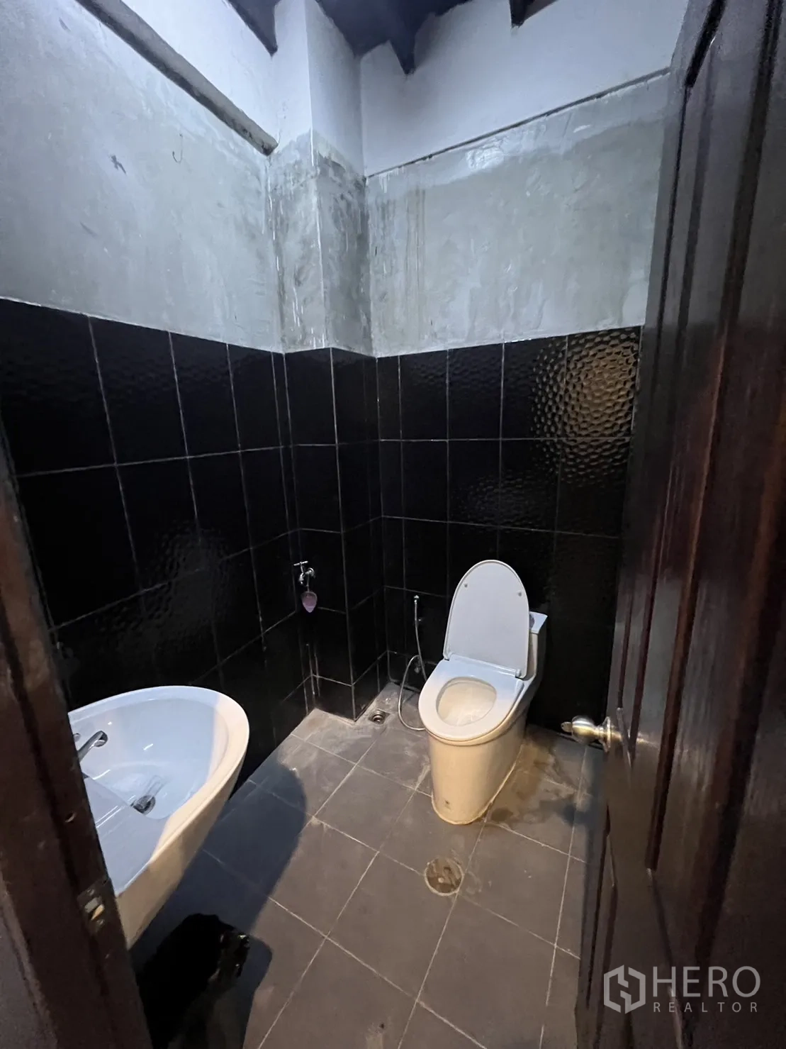 店屋 出租在Watthana, Bangkok - 深色墙砖卫生间，白色台盆与坐便器。