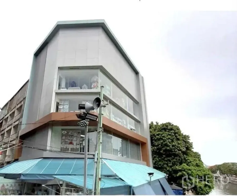 Shophouse for rent in Pathum Wan, Bangkok - Angled exterior view of a multi-storey shophouse showcasing large display windows and clean lines.