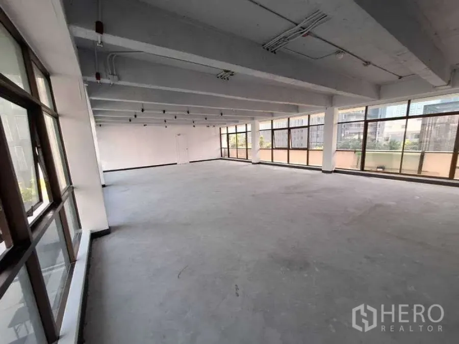 Office Space for rent - Open workspace with wide pillar spans, white walls, and panoramic windows providing abundant natural light.