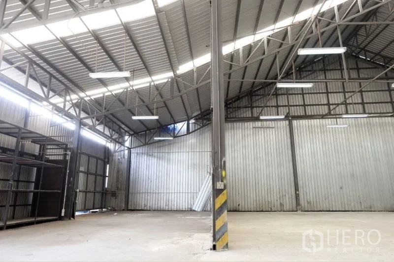 Warehouse for rent in Pak Kret, Nonthaburi - Clear-span warehouse area with a striped safety column and metal walls.