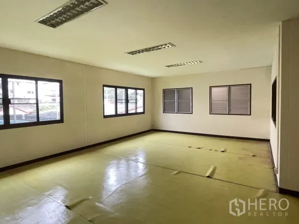 Warehouse for rent in Lat Phrao, Bangkok - Bright office room with multiple windows, drop ceiling and vinyl flooring.