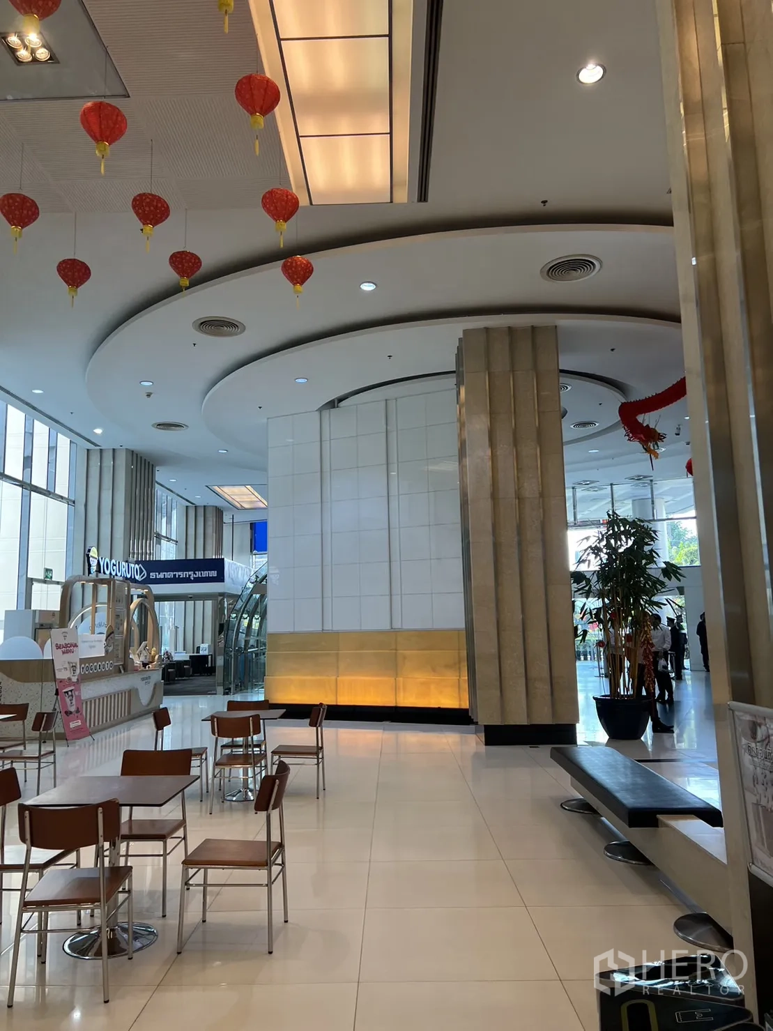 Retail Space for rent in Khlong Toei, Bangkok - Spacious mall concourse with curved ceiling details, lantern decor, a cafe kiosk and seating near a glass entrance.