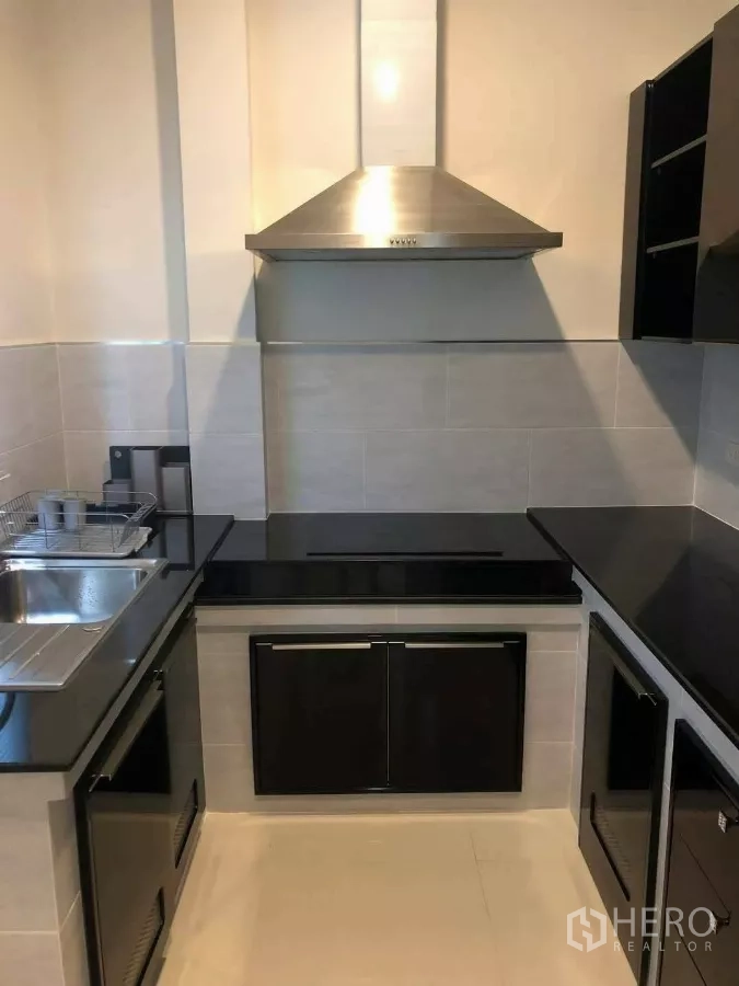 Detached House for rent or sale in Prawet, Bangkok - Compact kitchen with black countertops and stainless steel range hood