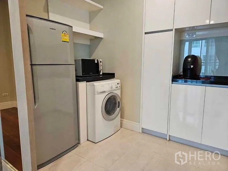 Condominium for rent or sale in Khlong Toei, Bangkok - Utility corner with tall fridge, front-load washing machine, microwave and white cabinetry.