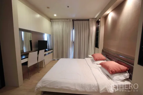 Condominium for rent in Khlong Toei, Bangkok - Master bedroom with king bed, long built-in desk, wardrobes and full-length curtains for privacy.