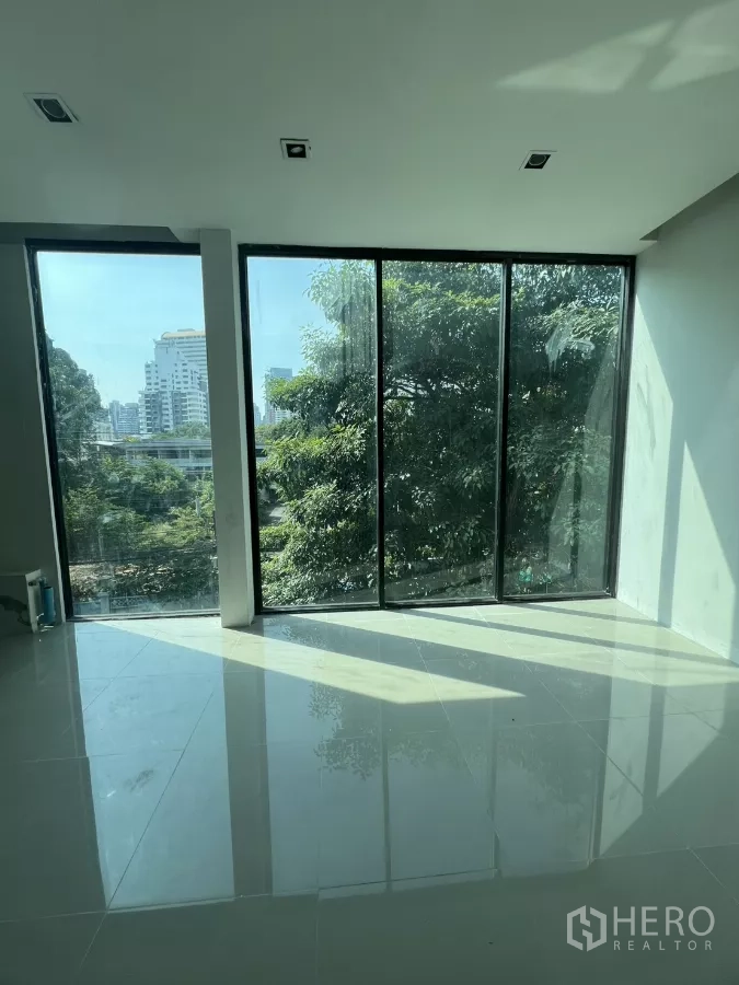 Retail Space for rent in Watthana, Bangkok - Sunlit corner space with large panoramic windows and shiny tiled floor facing mature trees.