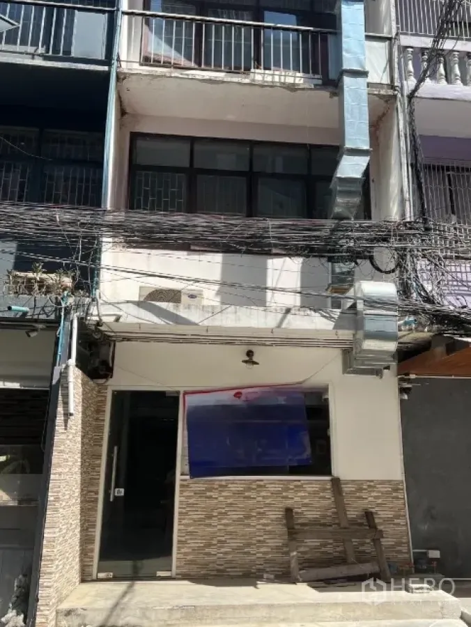 Shophouse for rent or sale - Front facade of a multi-storey shophouse with tiled entrance, ventilation ducting and overhead street cables.