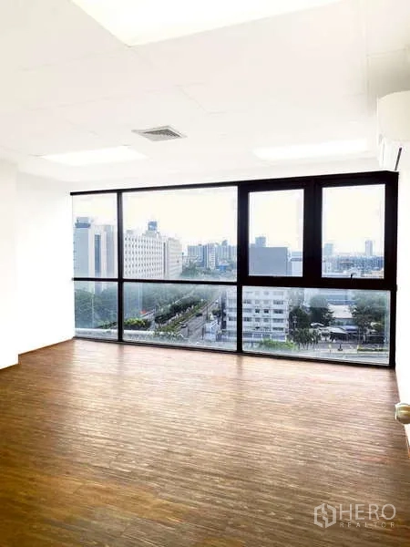 Office Space for rent - Bright open-plan office with floor-to-ceiling windows and city skyline views over a main road.