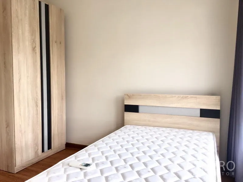 Townhouse for rent in Prawet, Bangkok - A cozy bedroom with a wood wardrobe and mattress by the window.