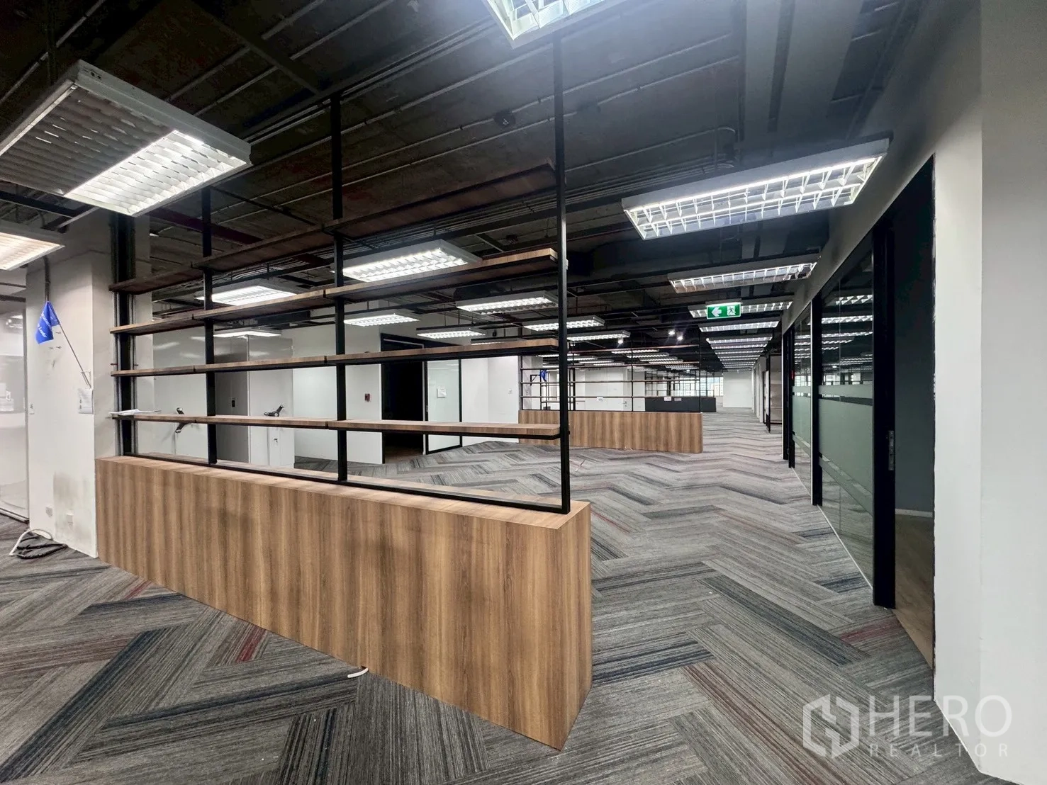 Office Space for rent in Watthana, Bangkok - Office area with a wood-and-metal shelving divider, glass-partitioned rooms, and overhead grid lighting.