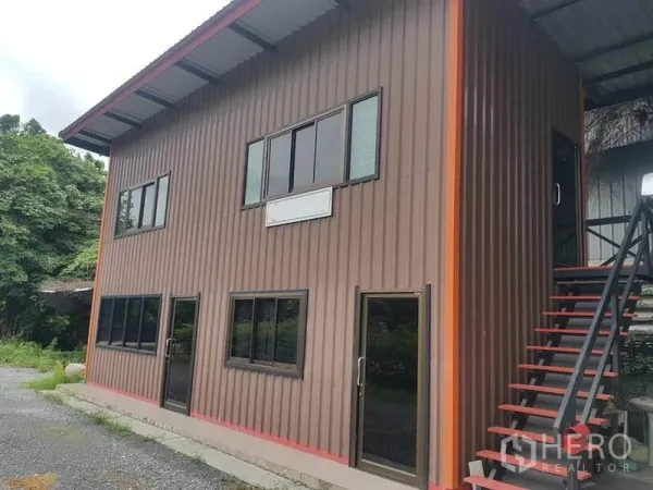 Warehouse for rent in Sai Noi, Nonthaburi - Two-storey metal-clad office building beside the warehouse with exterior stairs.
