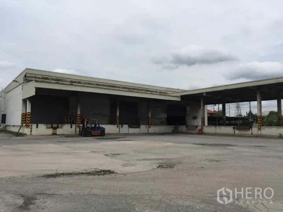 货栈 出租在Pathum Thani - 仓库外立面配有带雨棚装卸月台，车道宽阔，便于叉车与卡车进出。