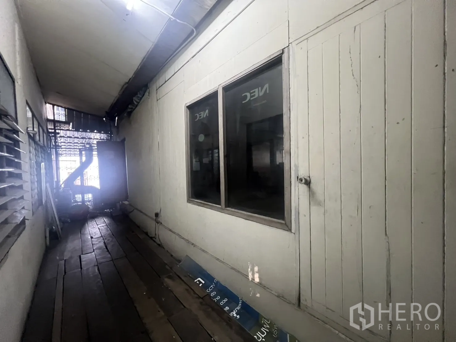 Shophouse for rent - Narrow corridor with wooden flooring, louvered windows and utility wiring.