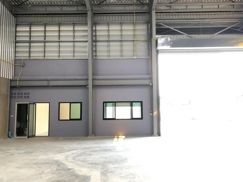 Factory for rent in Khlong Luang, Pathum Thani - Interior showing a ground-floor office block beneath a tall steel roof and wide roller door.