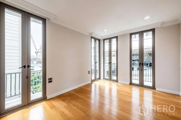 Townhouse for rent in Khlong Toei, Bangkok - Bright room with floor-to-ceiling French windows and warm wooden flooring.