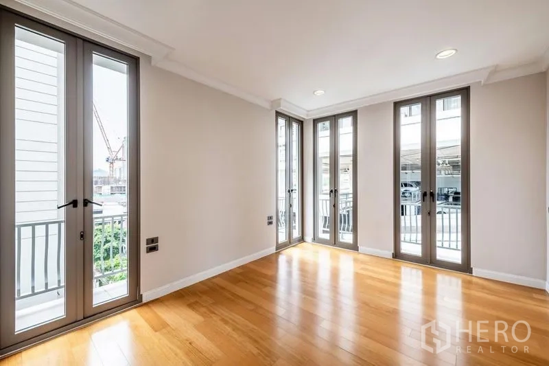 Townhouse for rent in Khlong Toei, Bangkok - Bright room with floor-to-ceiling French windows and warm wooden flooring.