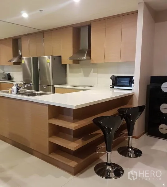 Condominium for rent or sale in Khlong Toei, Bangkok - Fully fitted kitchen with island counter, bar stools and built-in cabinetry.