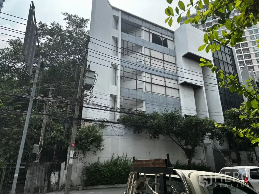Retail Space for rent in Bang Na, Bangkok - Multi-storey commercial building with wide street frontage on Sukhumvit Road in Bang Na, framed by trees and power lines.