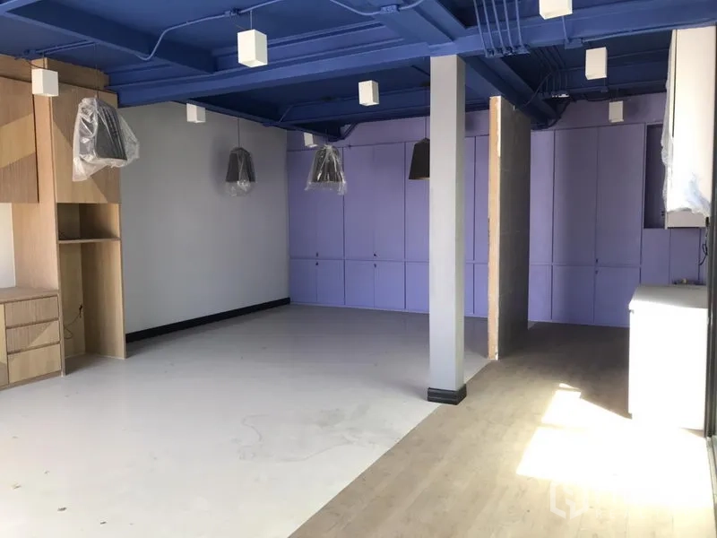 Retail Space for rent in Khlong Toei, Bangkok - Open-plan retail interior with blue exposed ceiling, built-in cabinets, pendant lights and mixed flooring.
