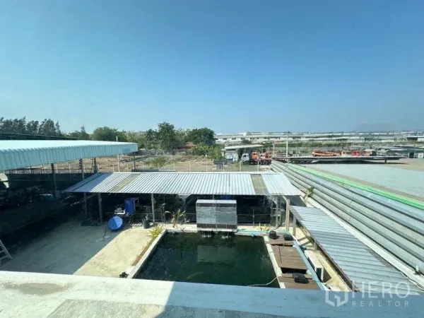 Warehouse for sale in Bang Phli, Samut Prakan - Elevated view showing a koi pond, covered work areas and the surrounding industrial zone.