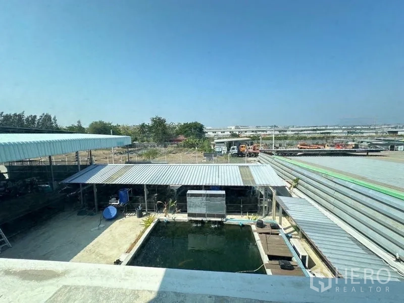 Warehouse for sale in Bang Phli, Samut Prakan - Elevated view showing a koi pond, covered work areas and the surrounding industrial zone.