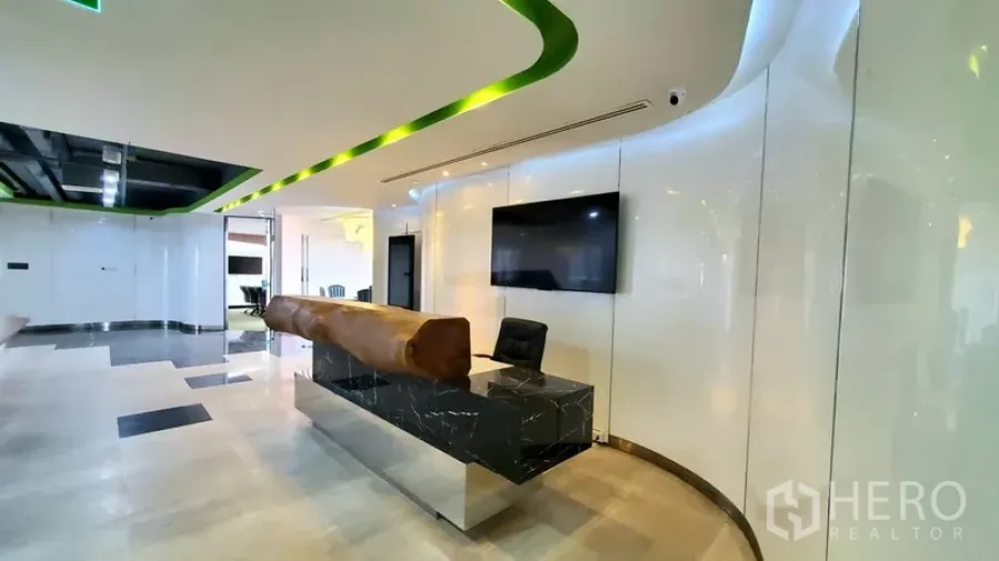 Office Space for rent in Watthana, Bangkok - Modern office reception with marble counter, curved LED ceiling detail and wall-mounted screen.