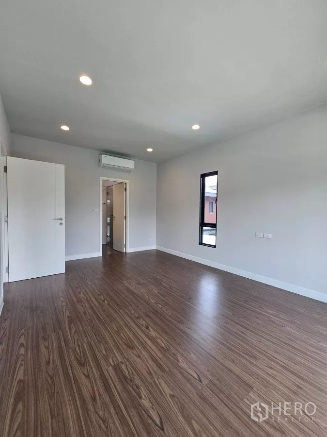 Detached House for sale in Lam Luk Ka, Pathum Thani - Spacious bedroom with air conditioning and door to ensuite.