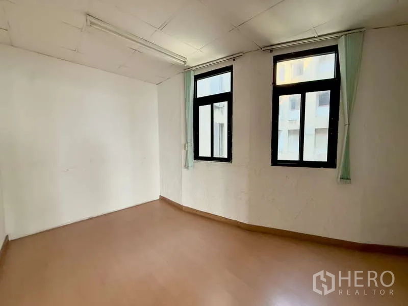 Office Space for rent in Chatuchak, Bangkok - Compact office with two tall windows and curtains, neutral walls and wood-look floor.