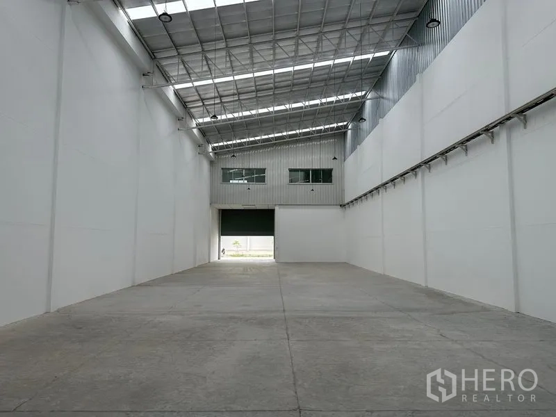 Factory for rent in Khlong Luang, Pathum Thani - Factory interior facing a wide roller shutter with office windows above