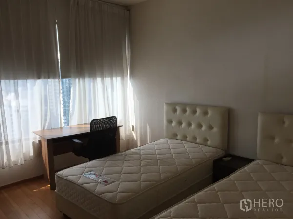 Condominium for rent or sale in Khlong Toei, Bangkok - Second bedroom with twin beds, study desk, wooden floor, and a large window with light curtains.