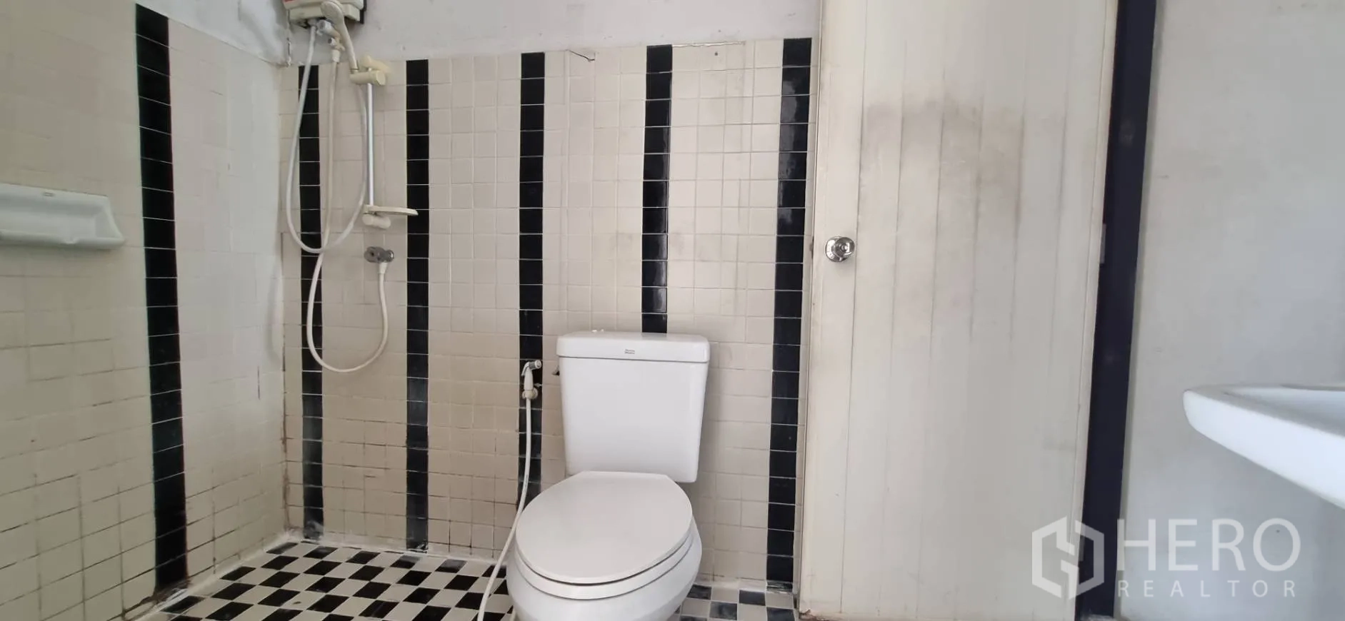 Shophouse for rent or sale in Bangkok - Bathroom with shower, toilet and black-and-white tiled walls and floor.