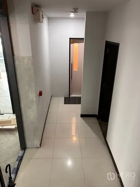 Office Space for rent in Khlong Toei, Bangkok - Clean interior corridor with glossy tiled floor, side doors and a lit glass door at the end.