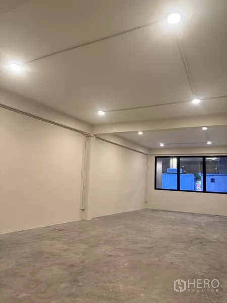 Shophouse for rent - Large rectangular room with window and ceiling lights, concrete flooring awaiting finishes.