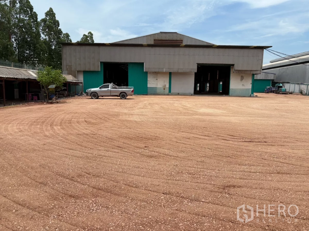 Factory for rent in Mueang Samut Sakhon, Samut Sakhon - Front elevation of the factory with a pickup truck and extensive compacted yard for trucks.