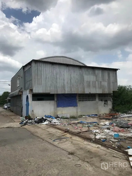 Warehouse for rent in Khlong Sam Wa, Bangkok - Side view of an older corrugated-metal warehouse with roller shutter and service lane.