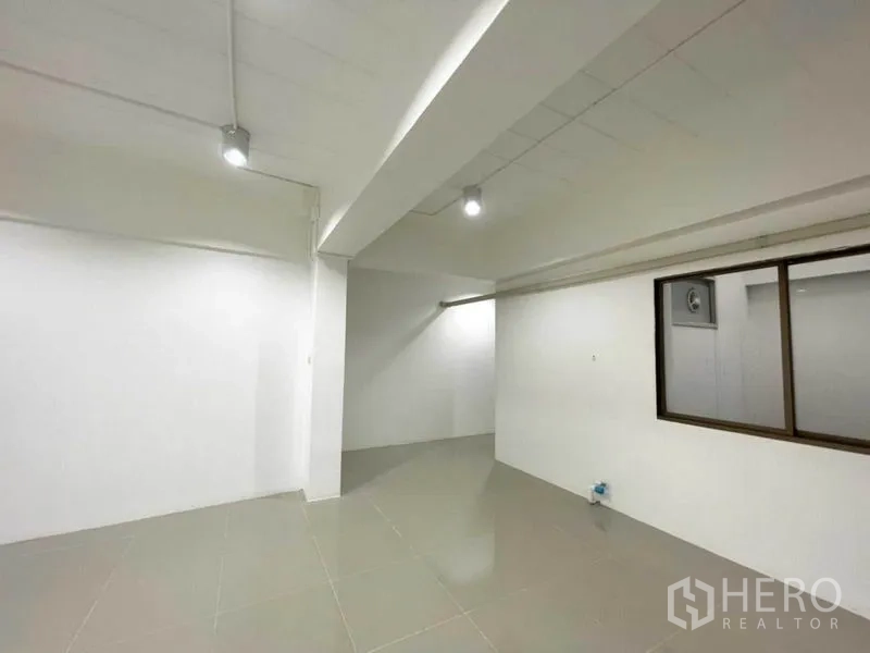 Office Space for rent in Khlong Toei, Bangkok - Office corner with white walls, ceiling beam and an interior window to a separate room.