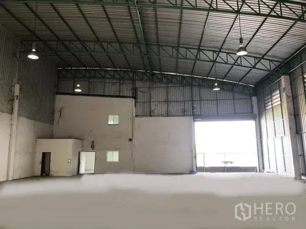 Factory for rent in Pathum Thani - Warehouse interior facing the large roller door with attached office block and high-clearance ceiling.