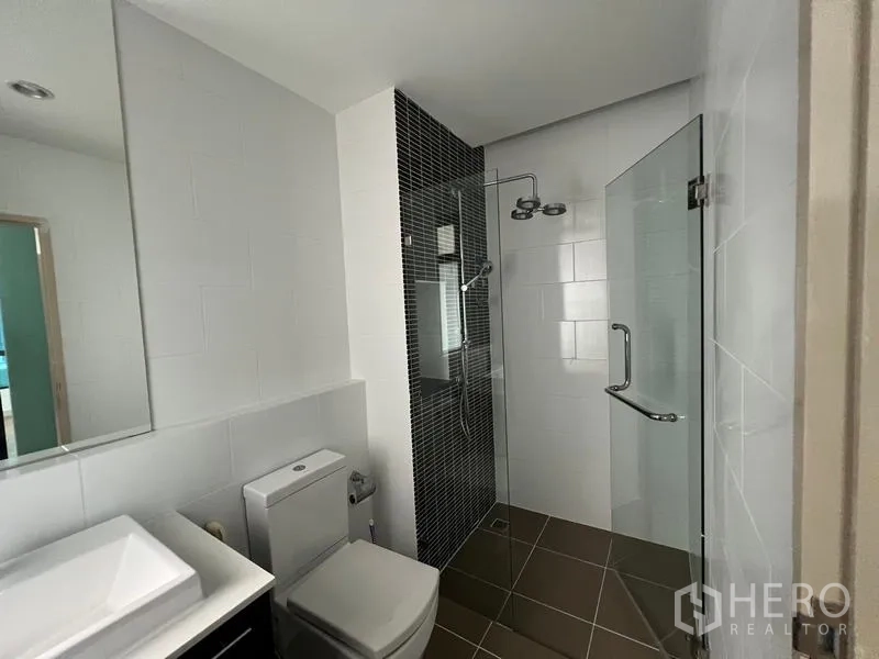 Townhouse for rent or sale in Khlong Toei, Bangkok - Full bathroom with walk-in glass shower, mosaic accent wall, and toilet.