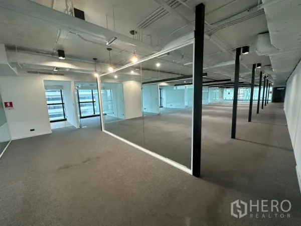 Office Space for rent - Large flexible workspace with glass meeting rooms, black columns and track lighting.