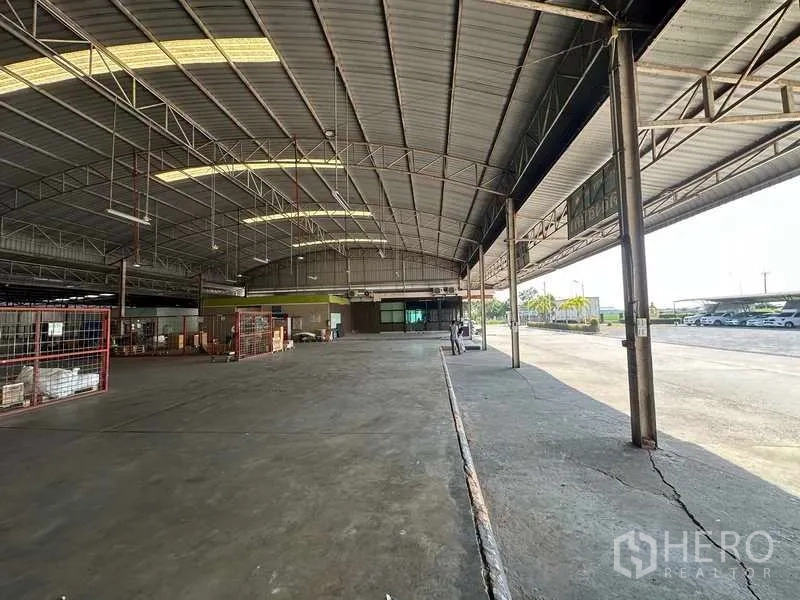 Warehouse for rent in Lam Luk Ka, Pathum Thani - Long interior aisle with storage cages opening to the yard through multiple bays.
