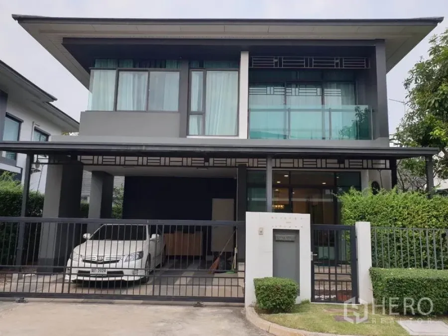Detached House for rent in Bang Kapi, Bangkok - Front exterior of a modern two-story detached house with gated fence, covered carport, and large glass windows.