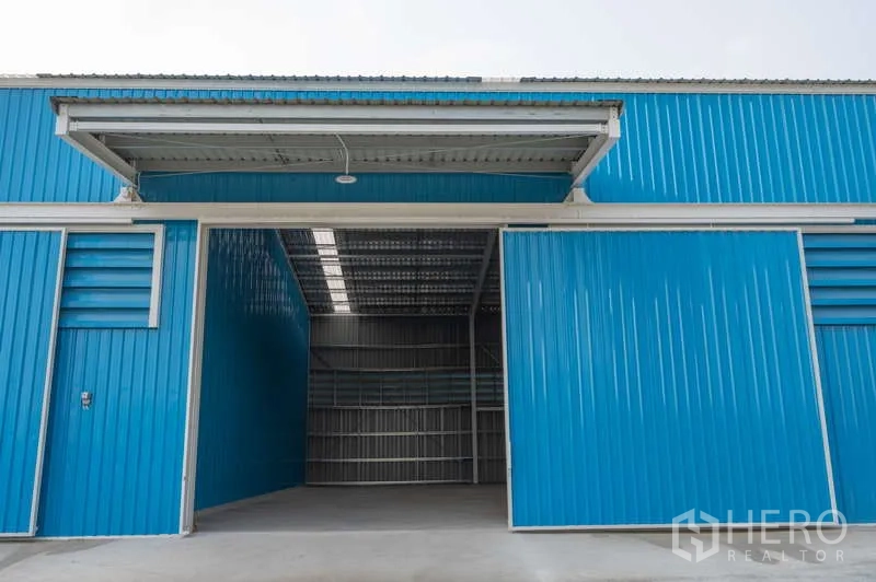Warehouse for rent in Khlong Luang, Pathum Thani - Open warehouse bay showing the high roof and steel structure beneath a covered canopy.