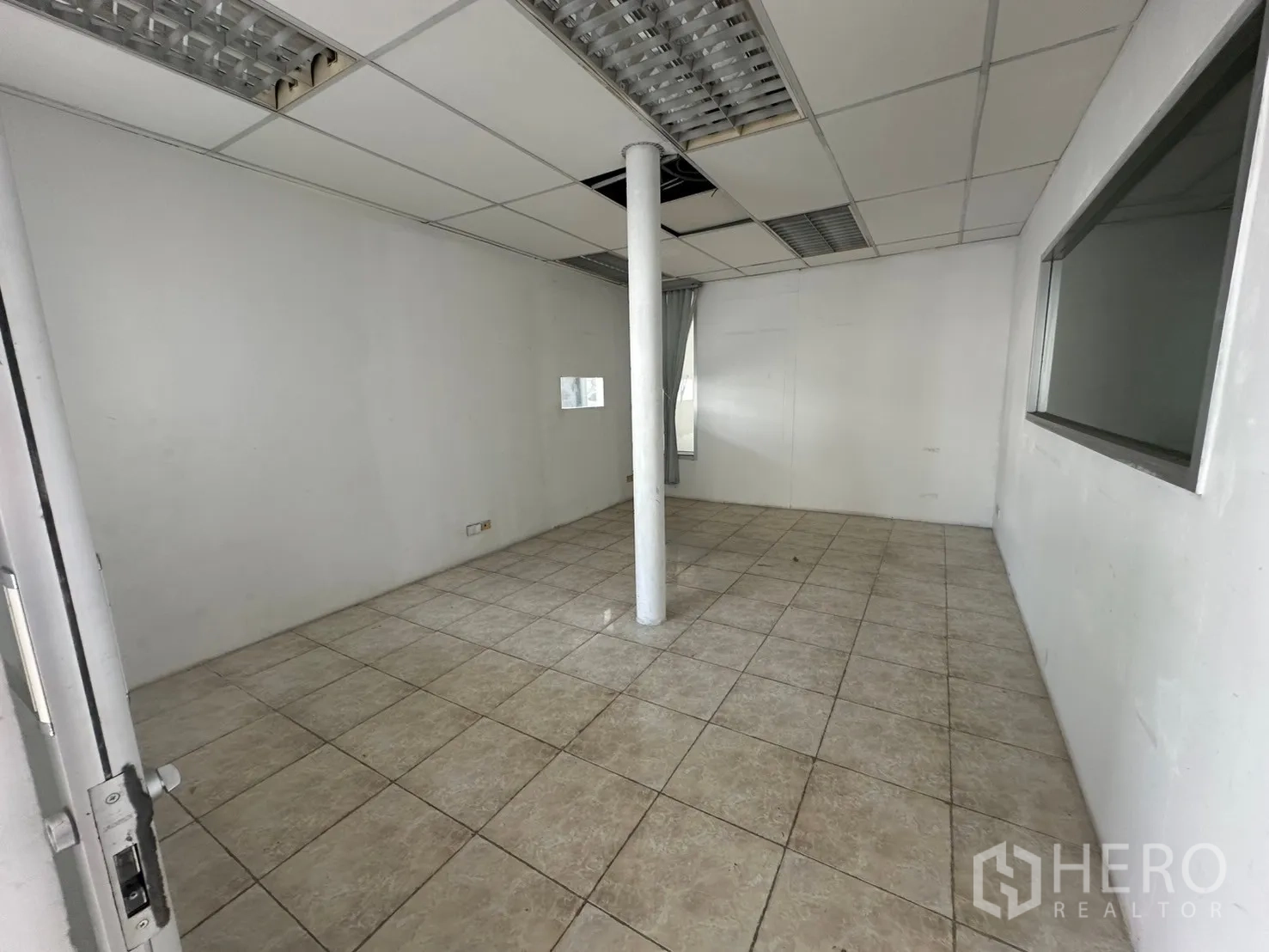 Warehouse for rent in Suan Luang, Bangkok - Tiled office room with drop ceiling and a central column.