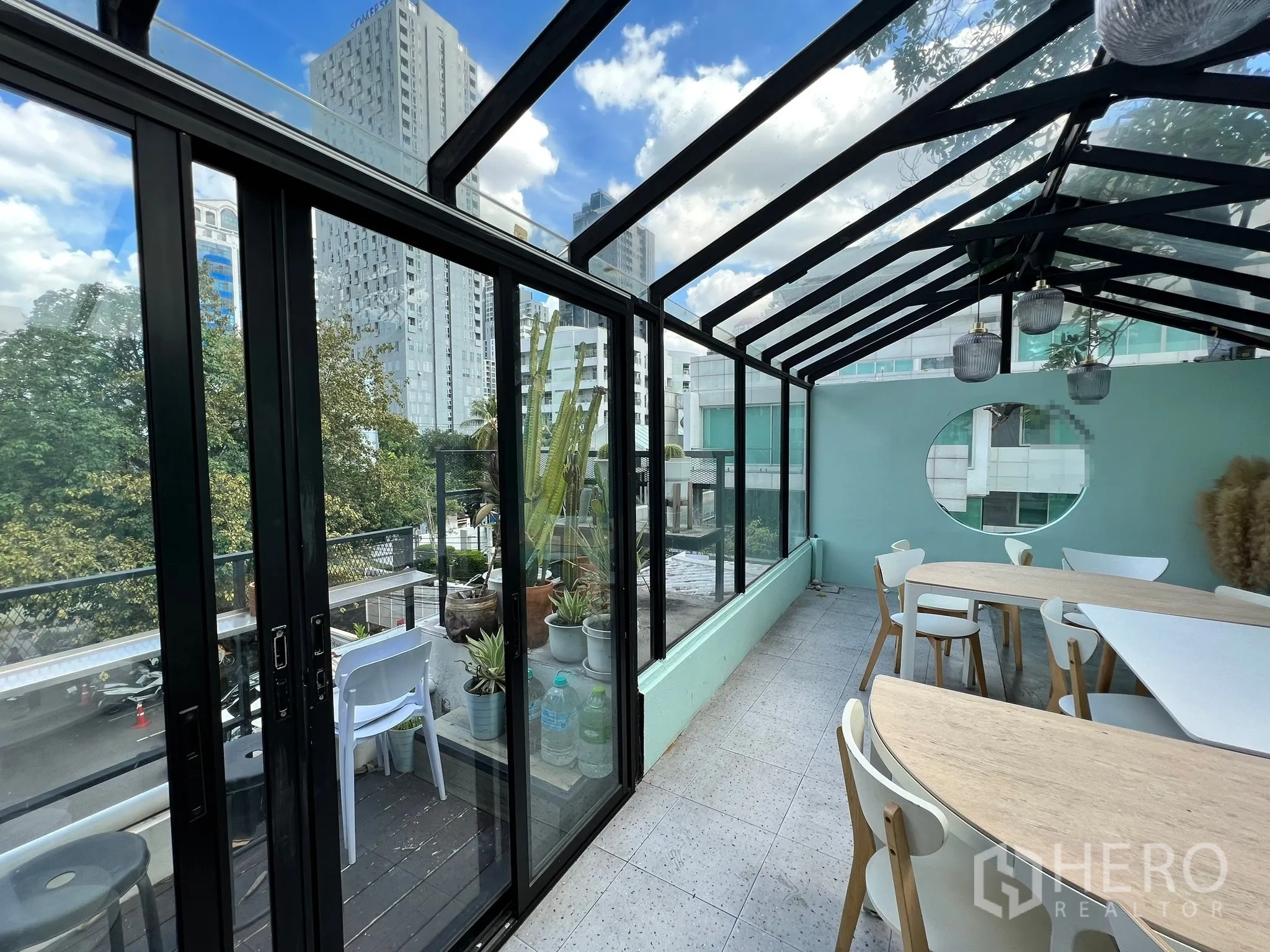 Retail Space for rent in Watthana, Bangkok - Sunlit glasshouse room with sliding doors to a balcony, city views and curved tables with white chairs.